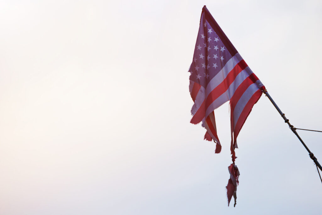 Torn American flag on the sky background